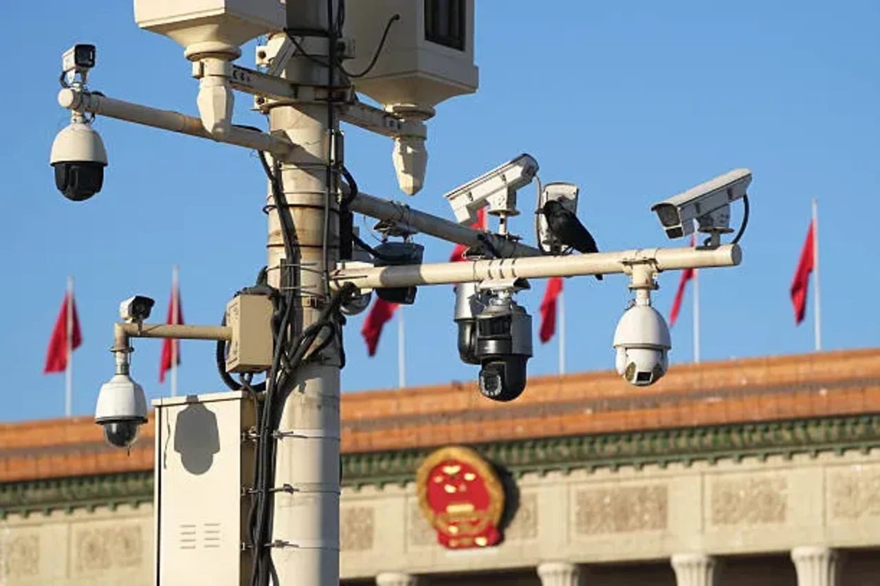 Cluster of surveillance cameras and sensors mounted on a city pole above a public square.